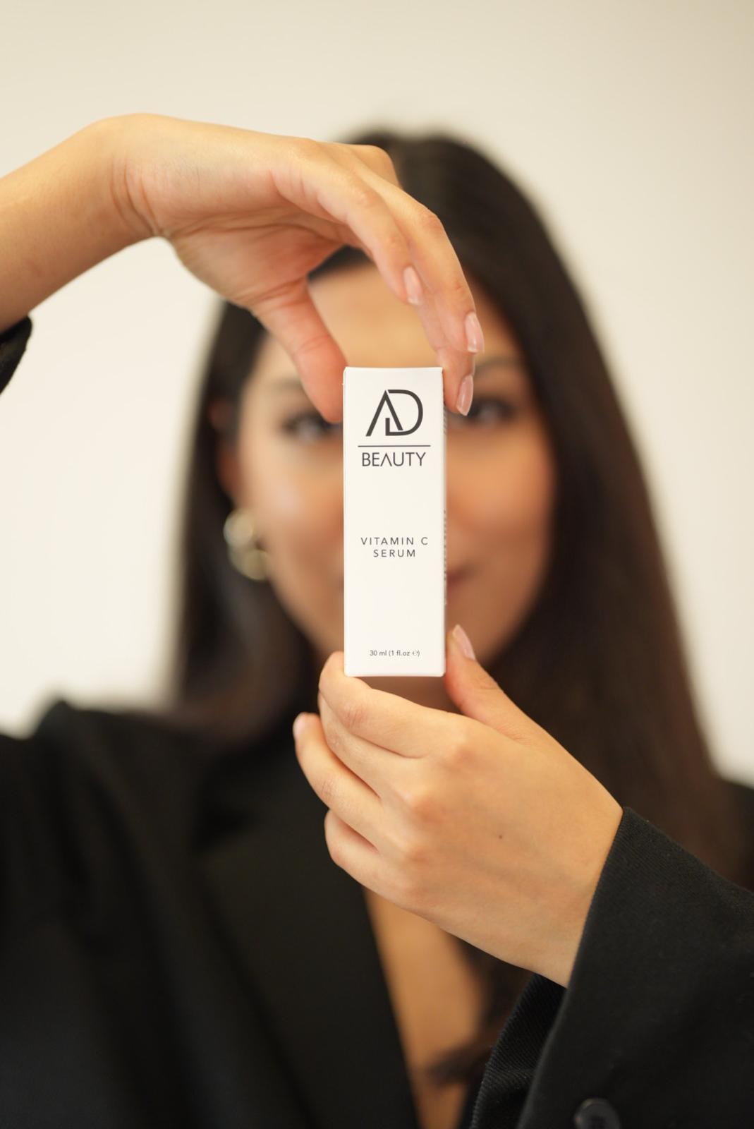 Model hält AD BEAUTY Vitamin C Serum vor das Gesicht – Hautpflege mit Glow-Effekt
