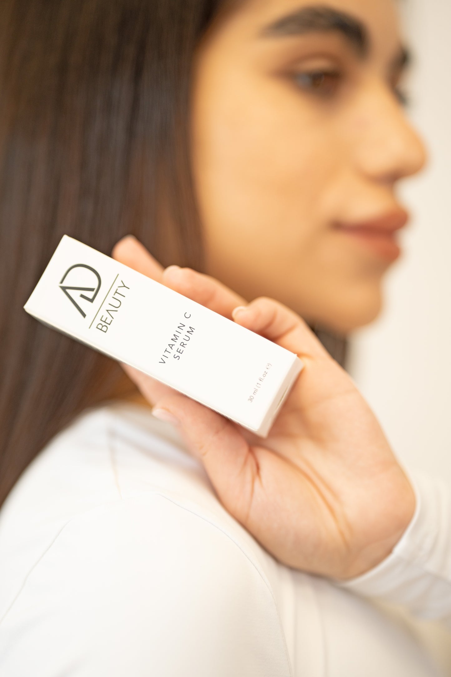 Das Modell präsentiert das geöffnete Vitamin-C-Serum elegant an ihrer rechten Schulter
